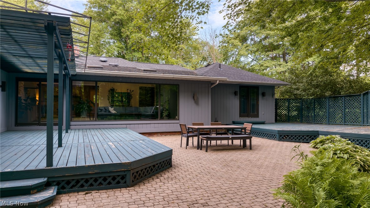 Home’s backyard patio with raised decks, outdoor dining furniture, and a broad window overlooking the living room.