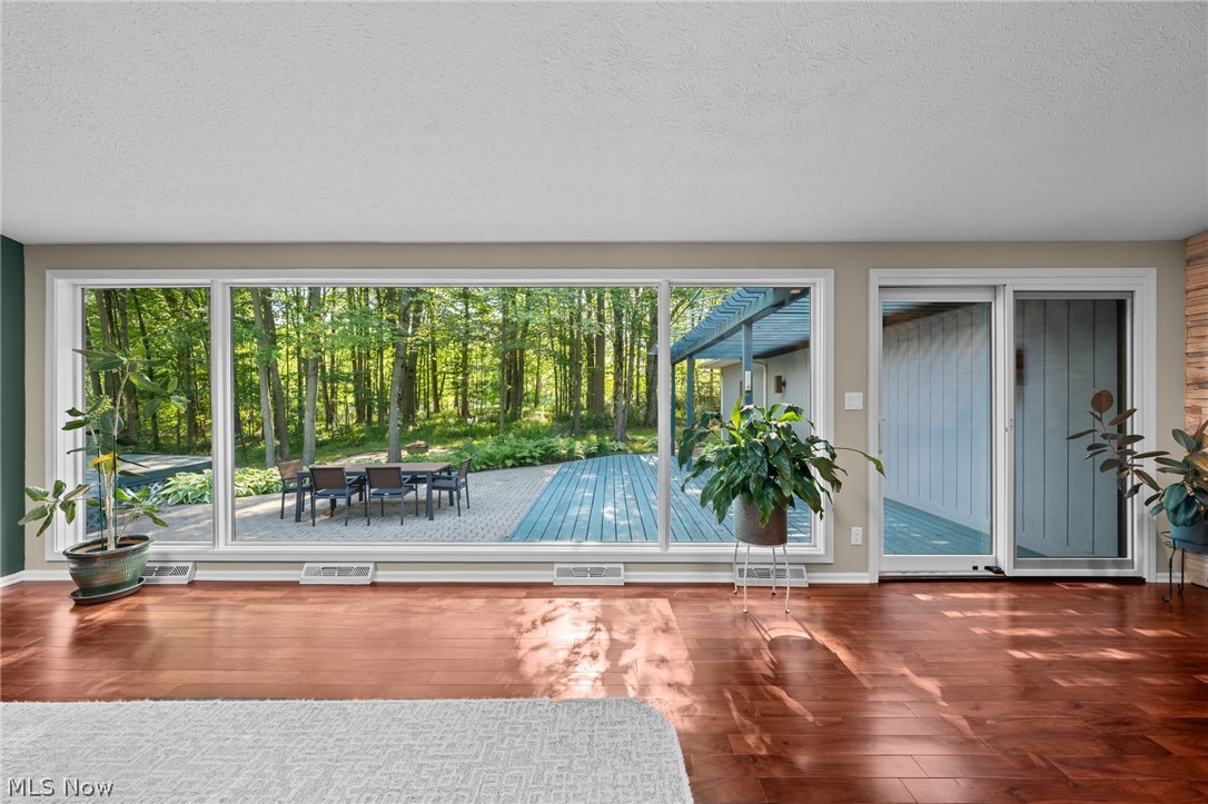 Living room with expansive windows overlooking a paved patio and wooded backyard.