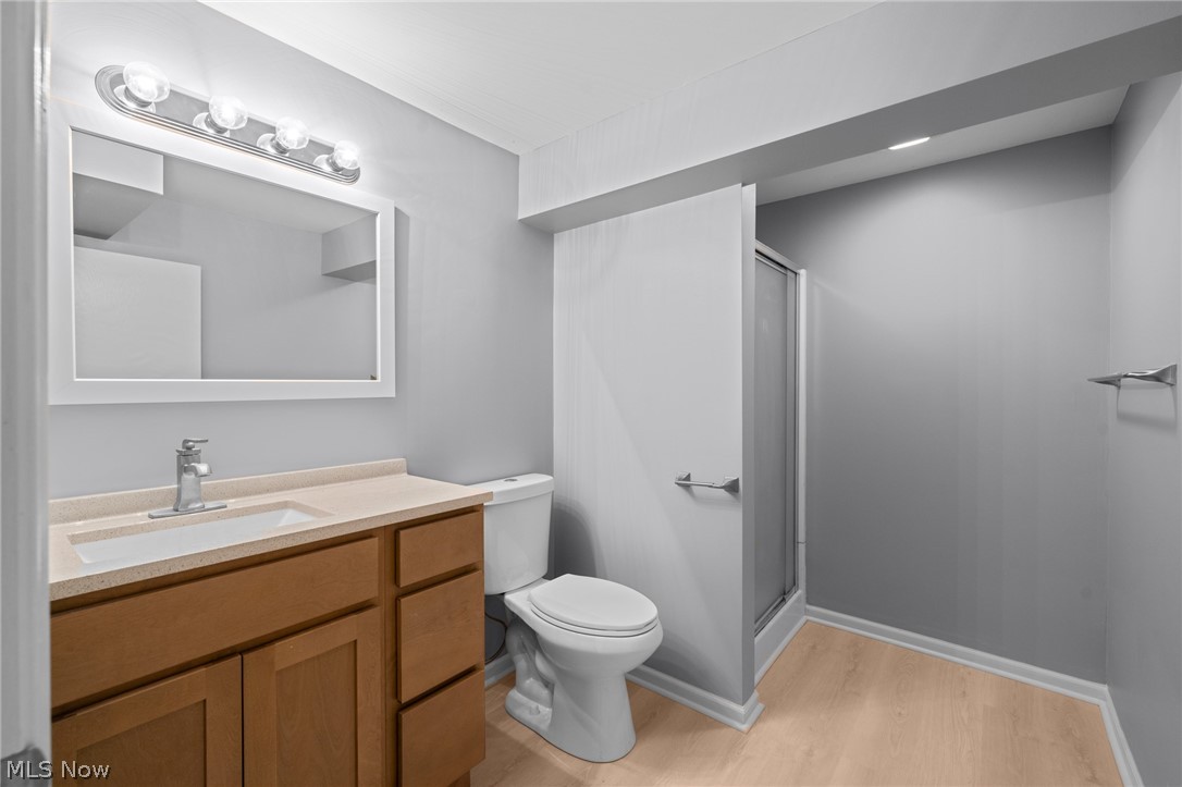 Bathroom with a wood vanity, large mirror, toilet, and glass-enclosed shower.