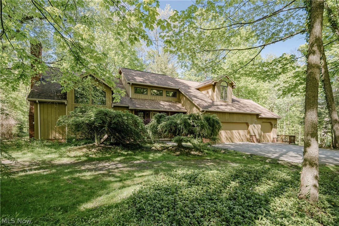 Wood-sided home with an attached two-car garage surrounded by mature trees.