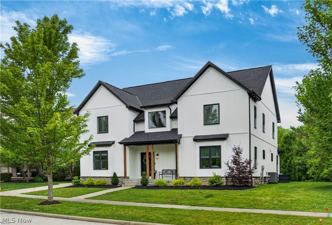 White two-story farmhouse with black trim, a covered wood-post entry, and a front lawn.