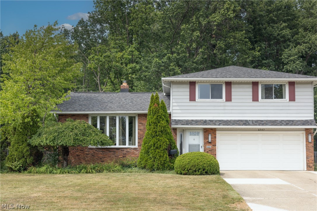 Two-story home with white siding, red shutters, brick lower level, and attached garage.