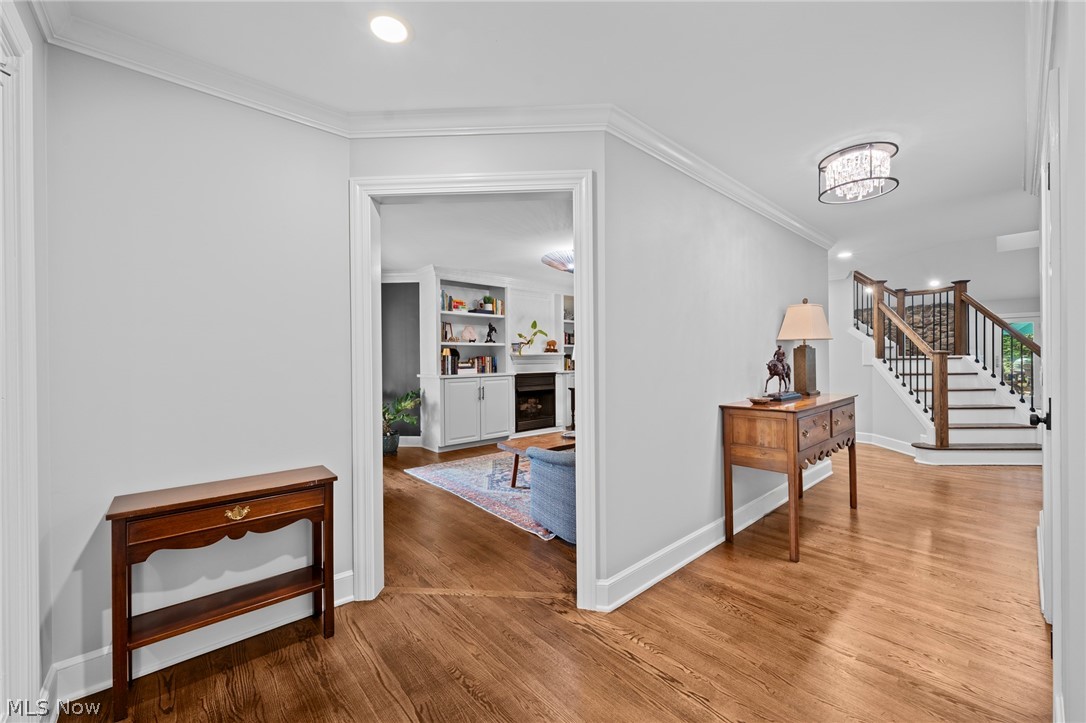 Foyer with hardwood floors, a staircase, and an open view into a living room with built-in shelves.
