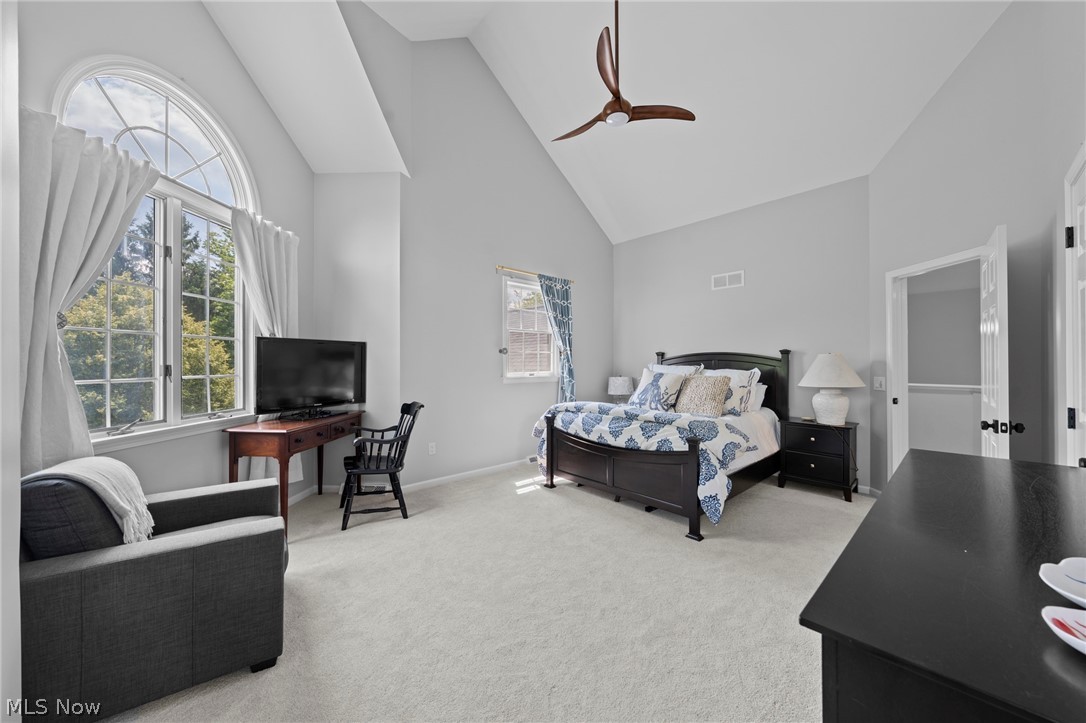 Furnished bedroom with vaulted ceiling, arched window, dark wood bed, and sitting area.