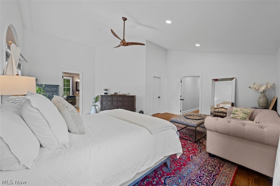 Bedroom with a large white bed, sitting area, patterned rug, and ceiling fan.