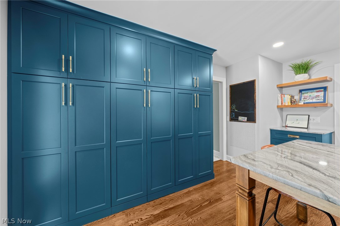Blue built-in cabinetry beside a marble-topped island and chalkboard workspace.
