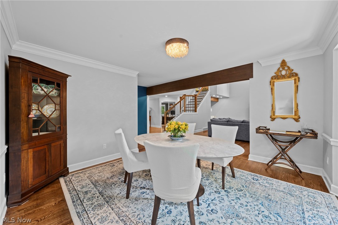 Dining room with a round marble table, white chairs, patterned rug, and dark wood china cabinet.