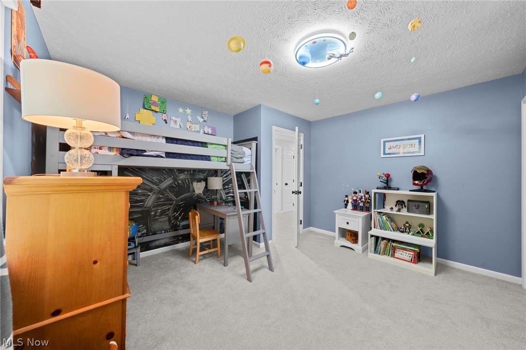 Blue bedroom with a raised bunk bed, space-themed wall mural, and shelves of books and toys.