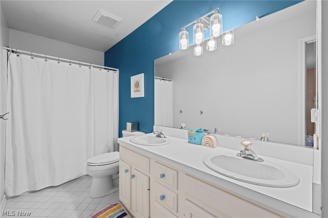 Bathroom with a double-sink vanity, large mirror, and blue accent wall.