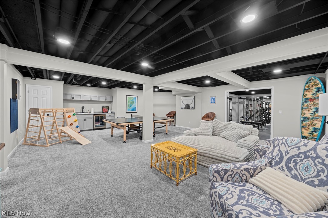 Finished basement recreation room with a kitchenette, table-tennis table, and open doorway to a home gym.