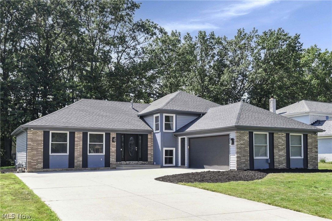 Blue-gray home with brick accents, a central entry, and an attached two-car garage.