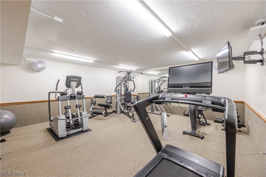 Building fitness room with treadmills, weight machines, and wall-mounted televisions.