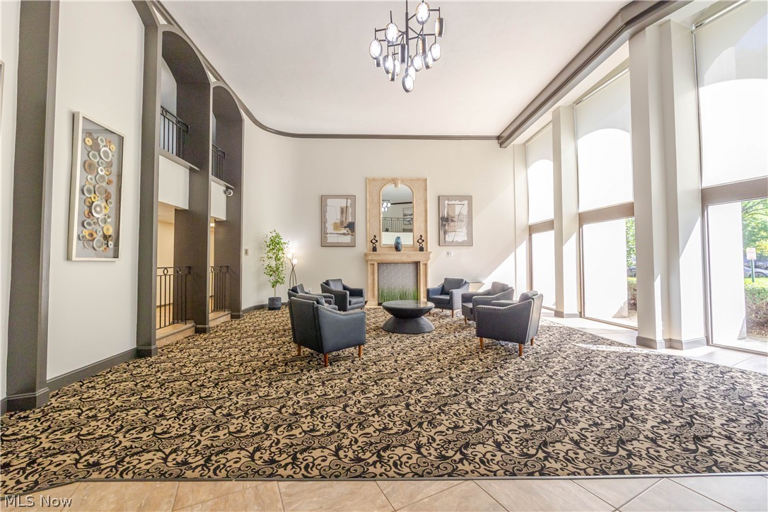 Lobby lounge with high ceilings, tall windows, fireplace, and patterned carpet.