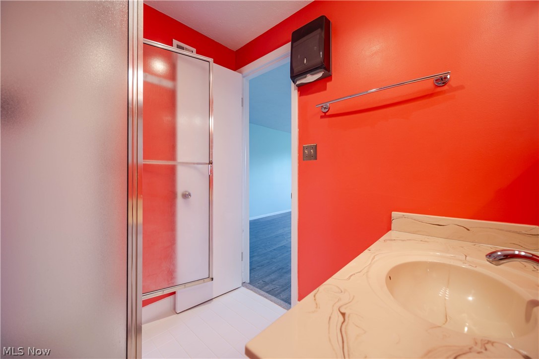 Bathroom with a cream marble-pattern vanity, glass shower enclosure, and vivid red walls.
