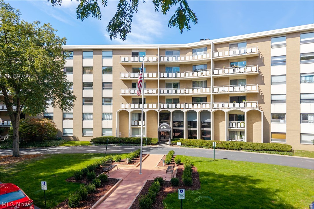 Condominium building with stacked balconies, a central entrance, and landscaped grounds.