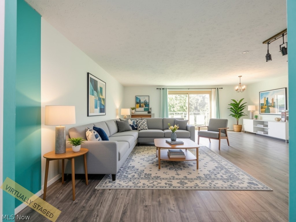 Living room with a gray sectional, patterned rug, and bright windows; virtually staged.