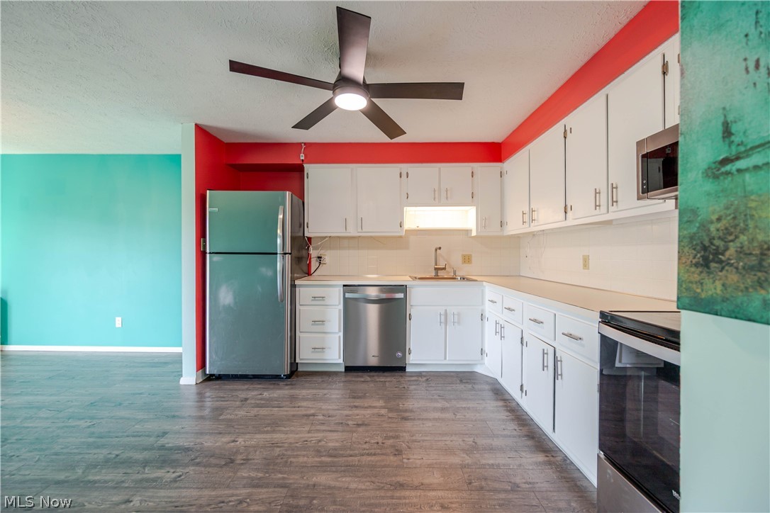 Kitchen with white cabinets, stainless steel appliances, and a turquoise and red accent wall.