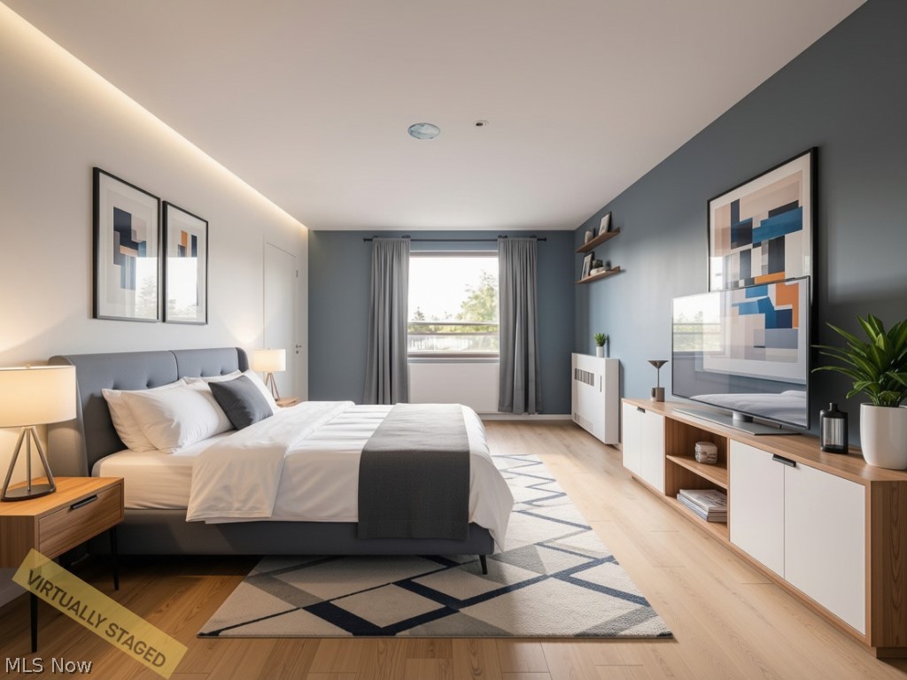 Virtually staged bedroom with a gray upholstered bed, geometric rug, and large window.