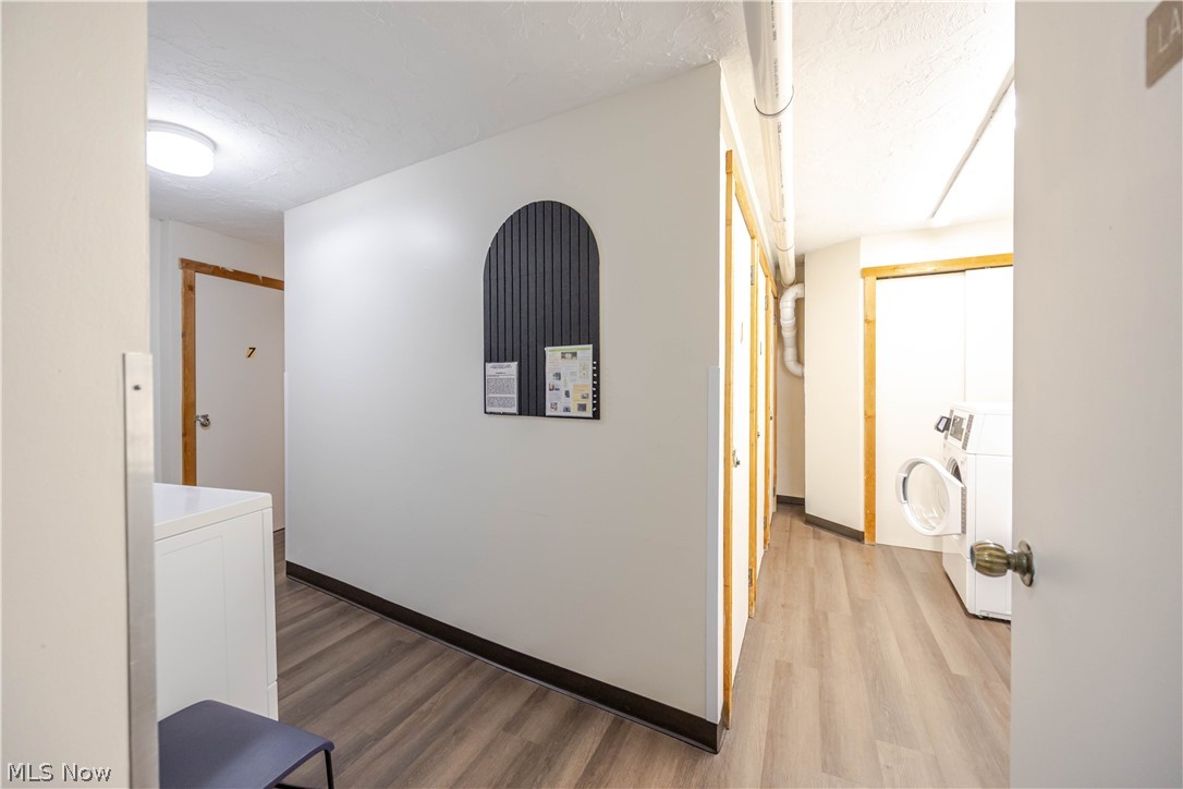 Shared laundry room with washers, wood-look flooring, and numbered doors.