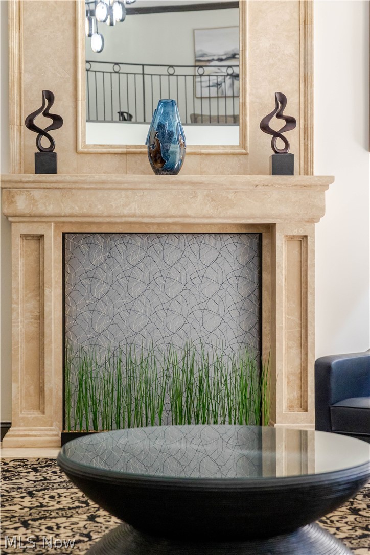 Living room fireplace with a marble mantel, blue vase, and decorative grasses.