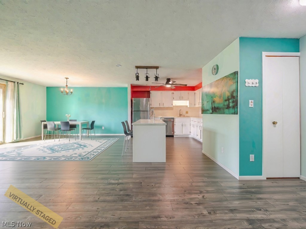 Open-plan kitchen and dining area with teal walls, white cabinetry, and wood-look flooring.
