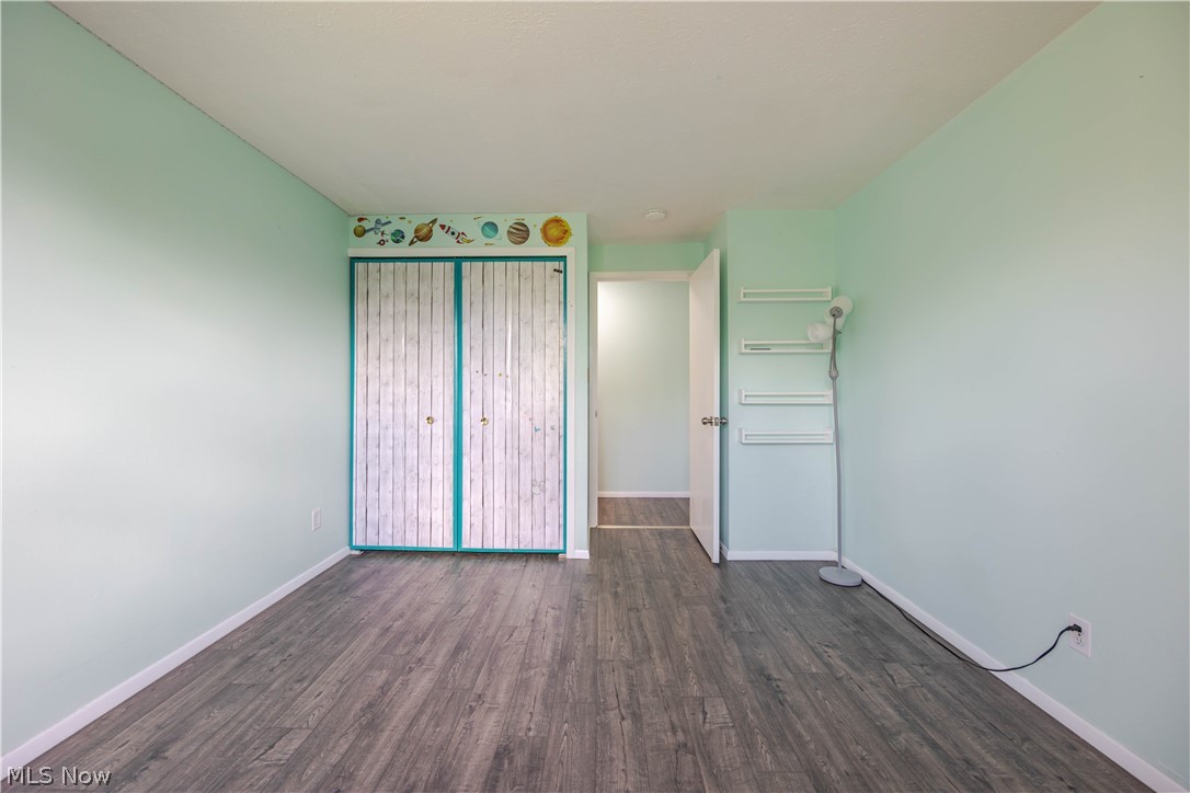 Vacant bedroom with pale aqua walls, wood-look flooring, and teal-trimmed closet doors.