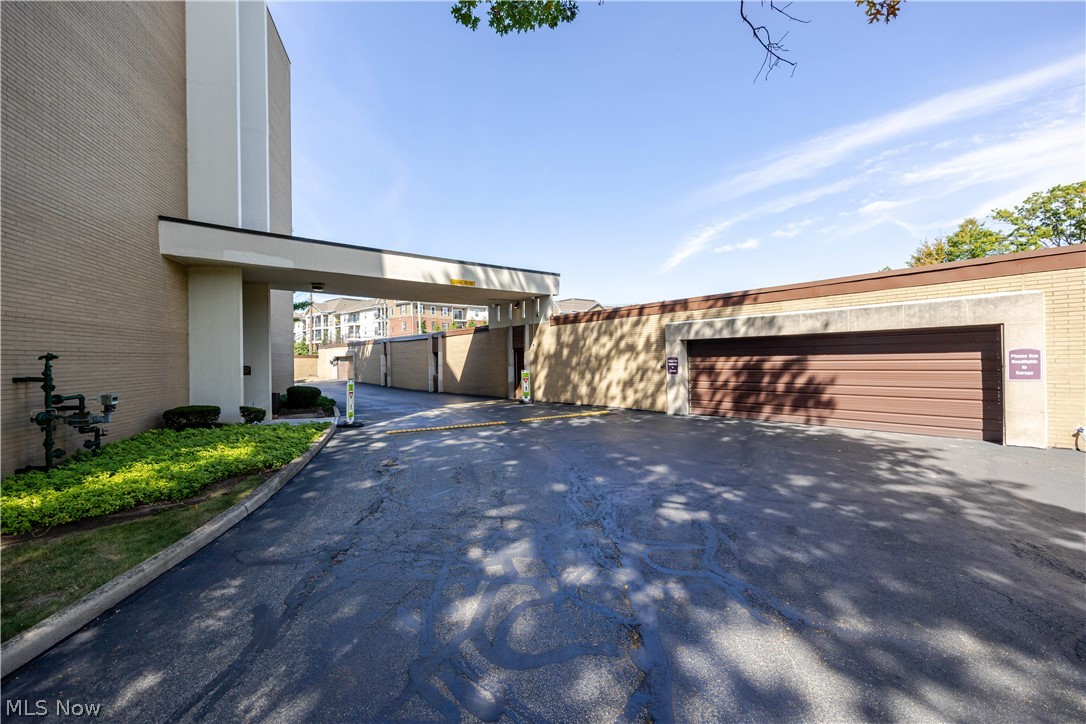 Building entrance canopy and garage beside a paved driveway.
