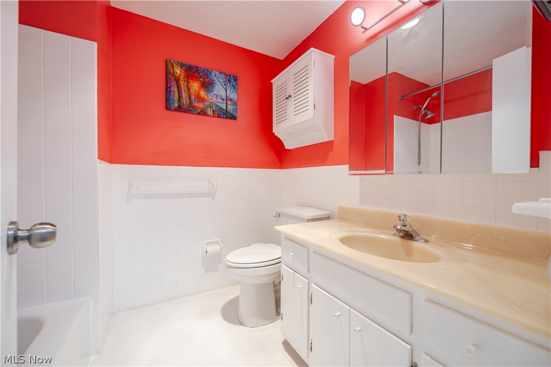Bathroom with vivid red walls, white vanity, mirrored cabinet, toilet, and shower.