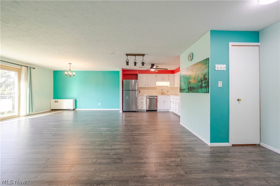 Open living area with gray plank flooring, turquoise walls, and a white kitchen.