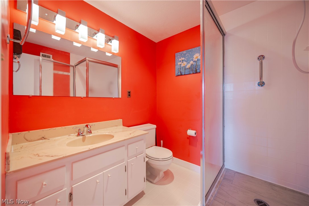 Bathroom with a white vanity, red walls, and a glass-enclosed shower.