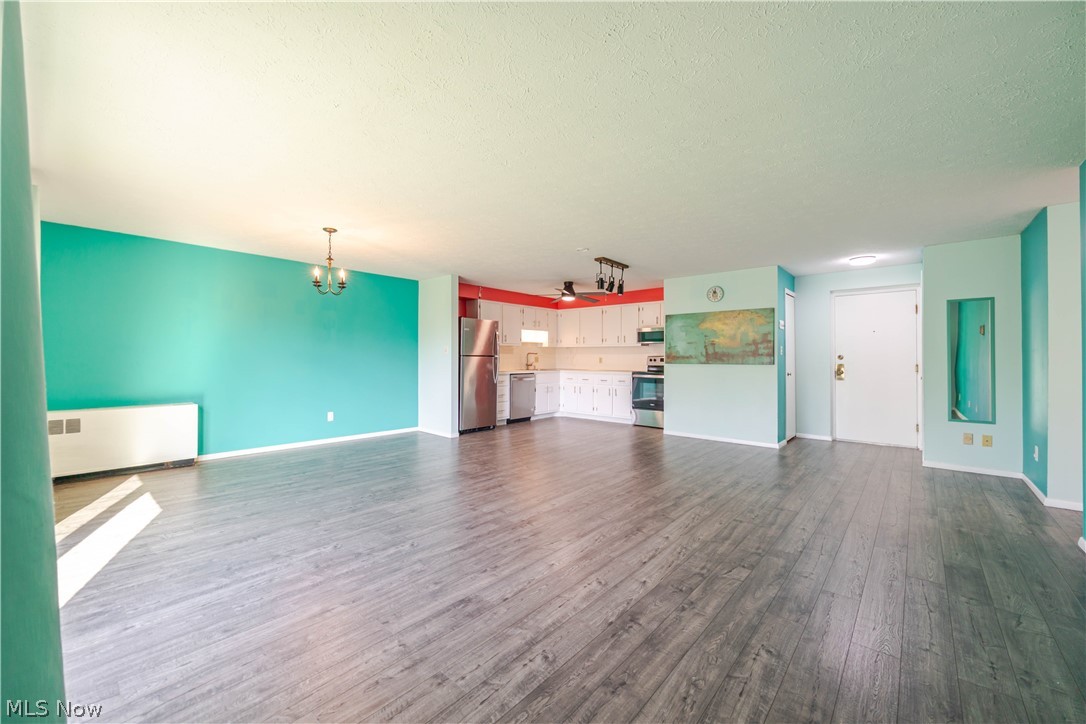 Open living and dining area with turquoise walls, gray plank flooring, and an adjoining white kitchen.
