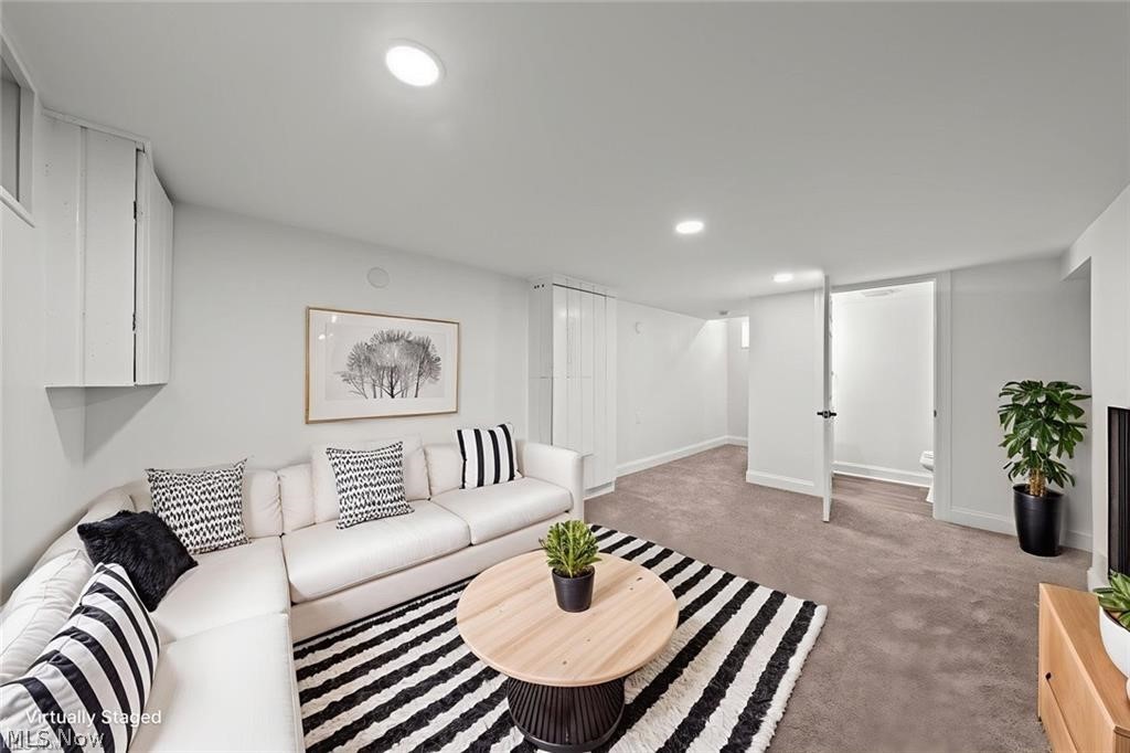 Virtually staged basement living room with white sectional, striped rug, and round coffee table.