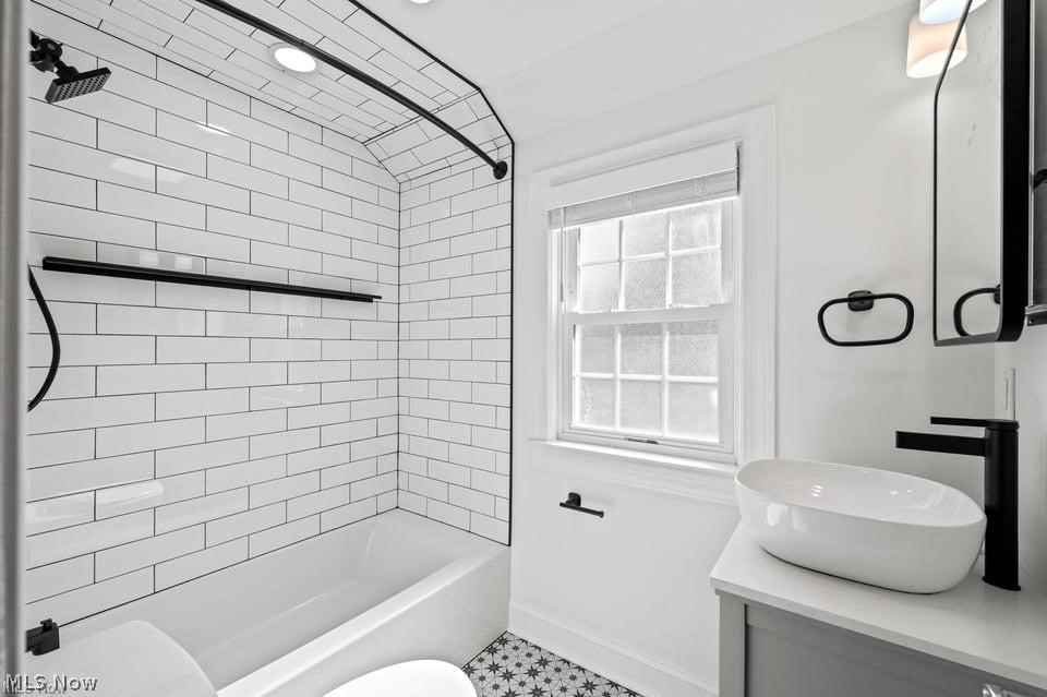Bathroom with a subway-tile tub, sunny window, vessel sink, and patterned black-and-white floor.