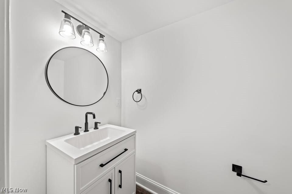 Bathroom vanity with a round mirror, black fixtures, and a three-light fixture.