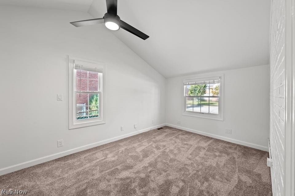 Empty carpeted bedroom with two windows and a ceiling fan with light.