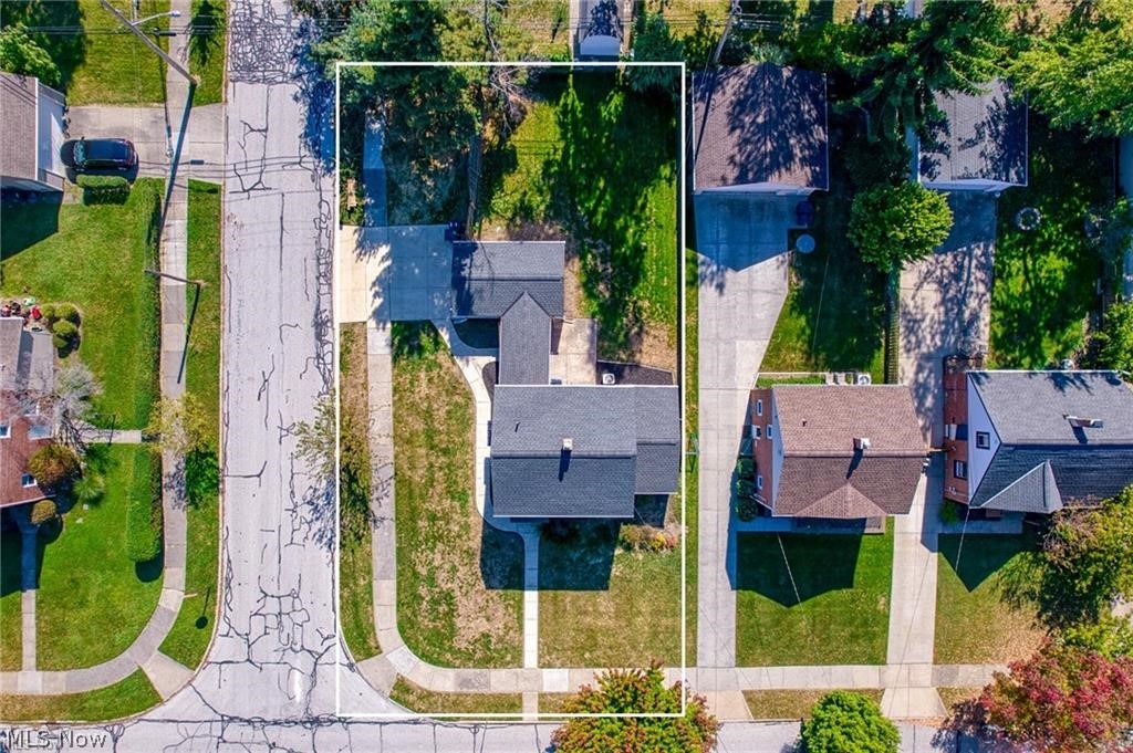 Aerial view of a house and its outlined lot on a tree-lined residential street.