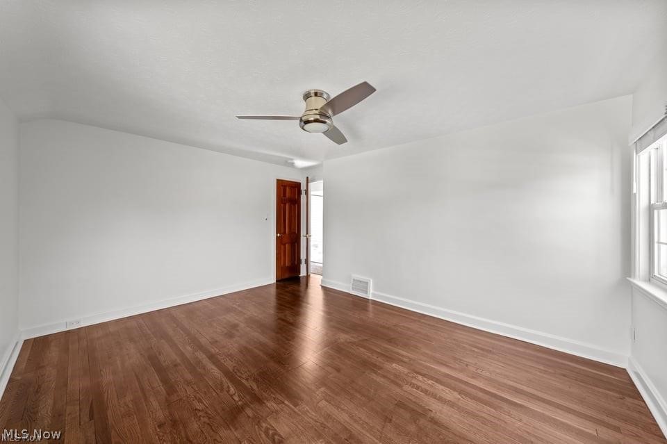 Empty room with hardwood floors, a ceiling fan, and a window.