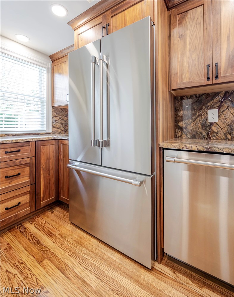 Kitchen with a stainless-steel French-door refrigerator, warm wood cabinetry, and hardwood floors.