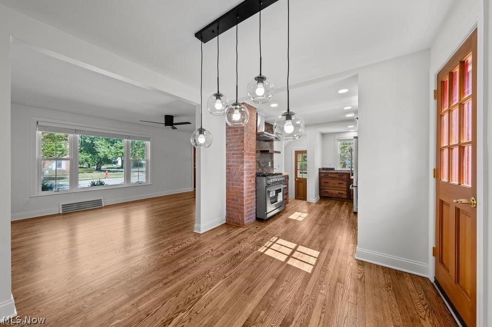 Open kitchen and dining area with hardwood floors, exposed brick column, and glass pendant lights.