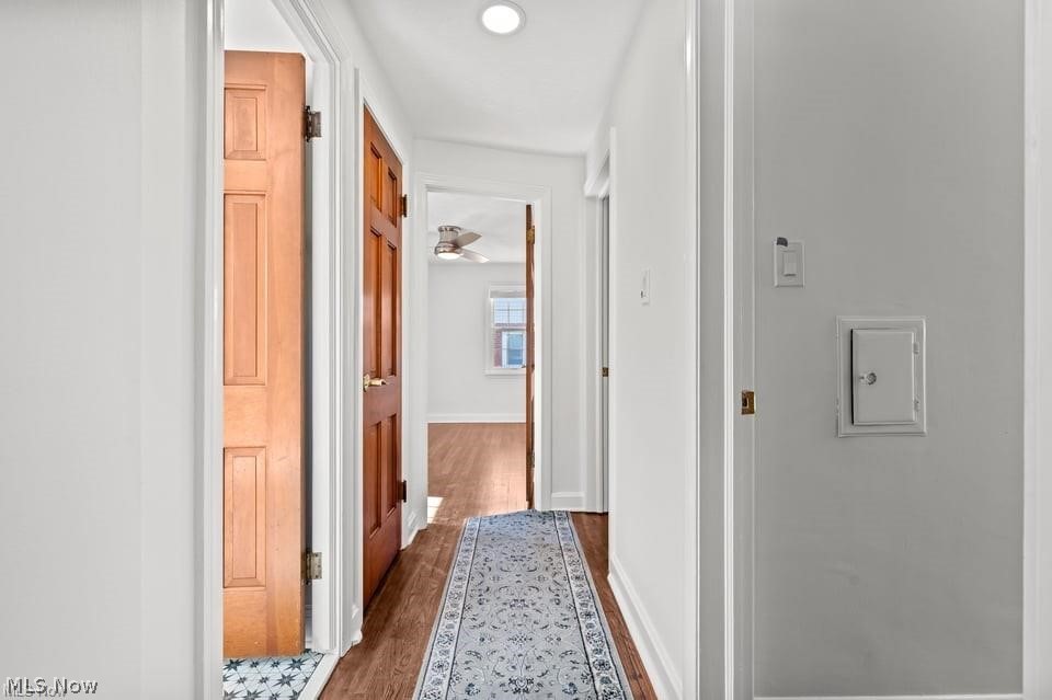 Hallway with hardwood floors, paneled wooden doors, and a patterned runner rug.