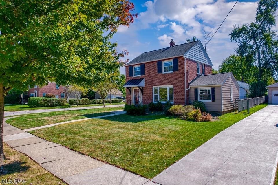 Two-story brick house with dark shutters, a light-sided extension, and a broad driveway.