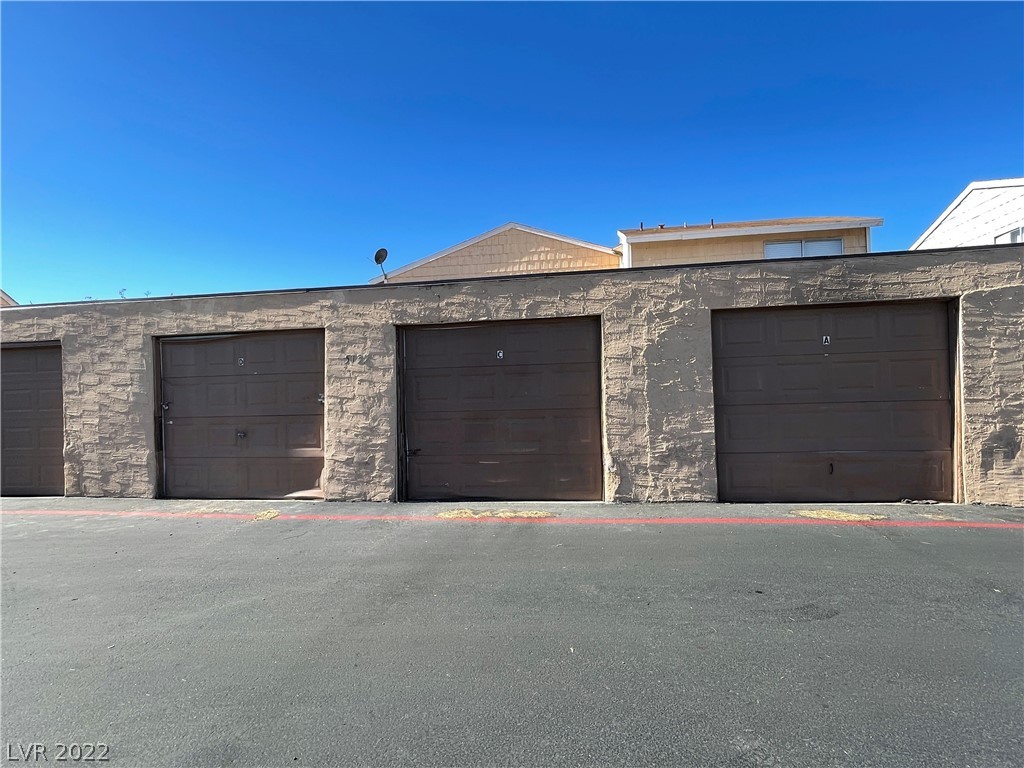Row of brown garage doors in a gray stone-textured wall.