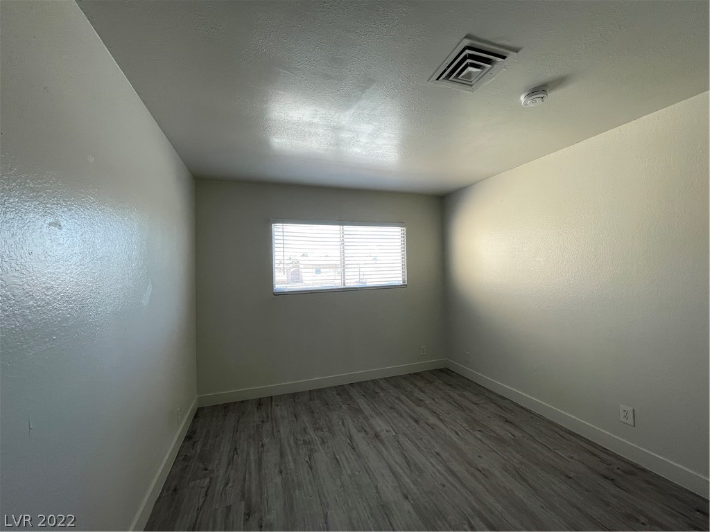 Empty room with gray wood-look flooring and a window with blinds.