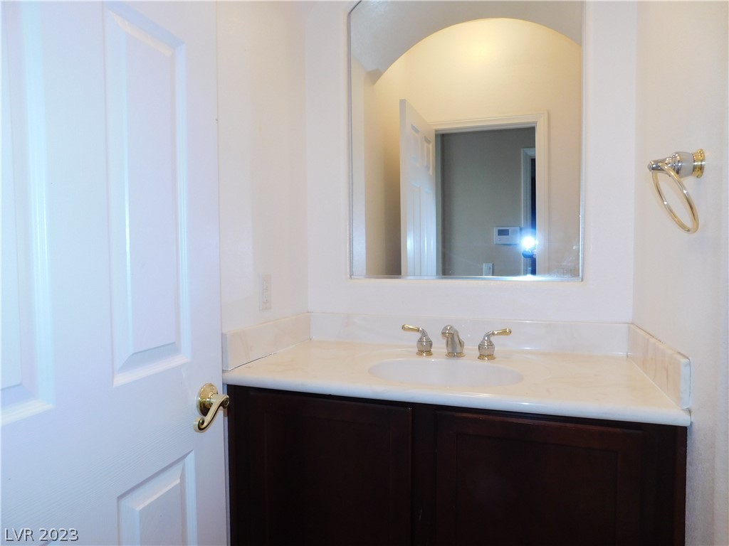 Bathroom vanity with a pale stone counter, dark wood cabinets, and a large mirror.