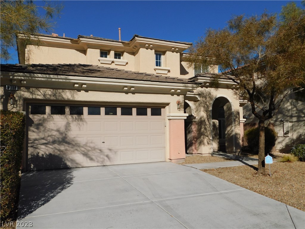 Two-story stucco home with a double garage, arched entry, and wide concrete driveway.