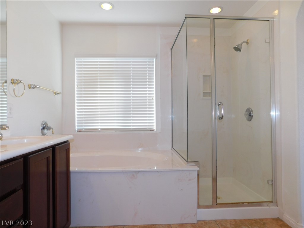 Bathroom with a soaking tub beneath a window and an enclosed glass shower.