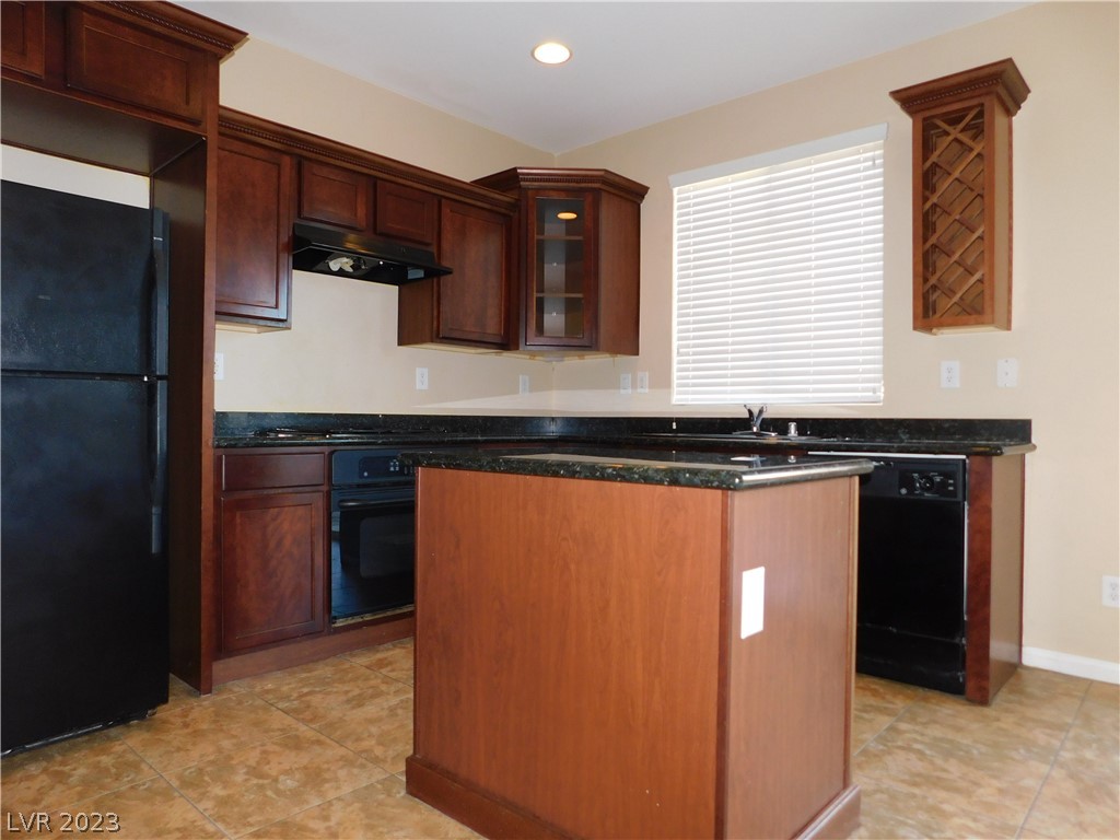 Kitchen with dark wood cabinets, black appliances, and a central island with a dark countertop.