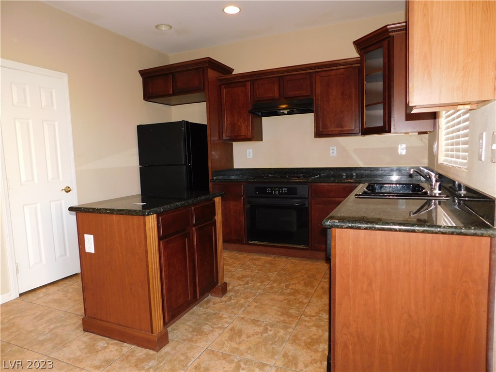 Kitchen with dark cherry cabinets, granite counters, a center island, and black appliances.