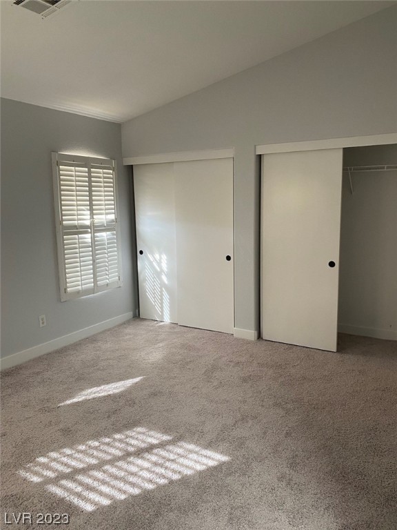 Empty bedroom with plantation shutters, sliding closet doors, and sunlight striped across the carpet.
