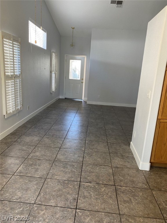 Empty room with a dark tiled floor, shuttered windows, and a glass-paneled door.